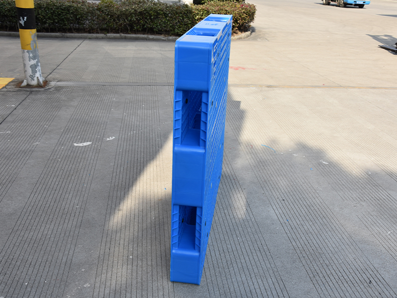 Reversible plastic pallet with dual-sided load-bearing surface in warehouse use