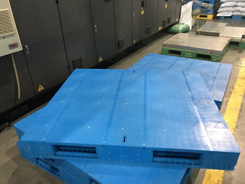 Stack of hygienic plastic pallets with solid deck and 3-runner bottom structure in a clean industrial facility, compliant with FDA and EU food contact standards.
