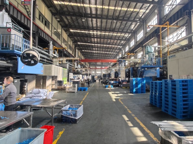 Plastic pallet under heavy load simulation with stacked weights and product bags in warehouse conditions, showing real-world structural testing.