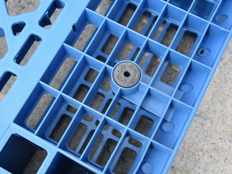 Close-up of grid deck plastic pallet equipped with rubber anti-slip inserts to prevent shifting in high-rack stacking environments.